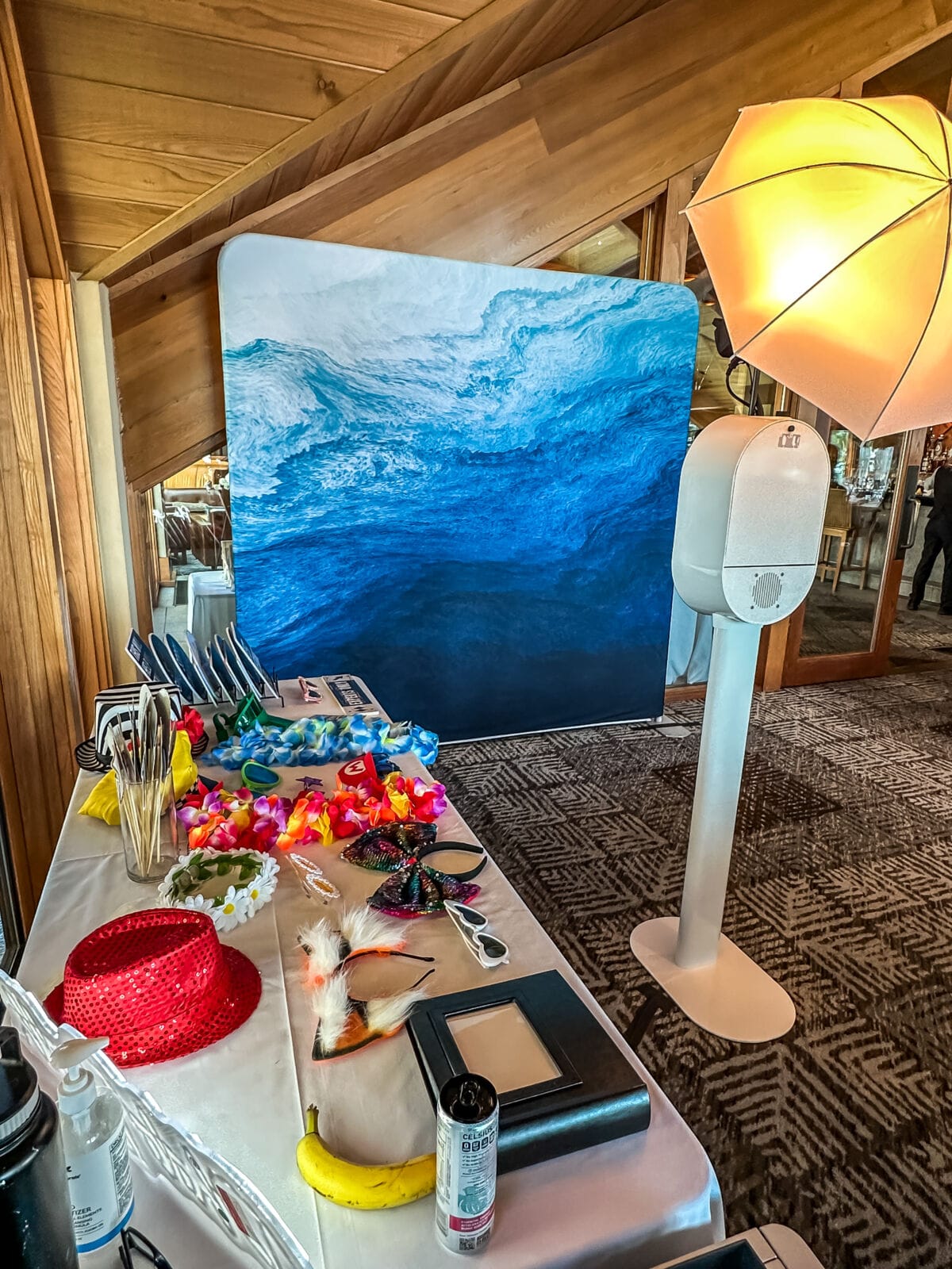 Photo booth with an ocean-wave backdrop and a table of colorful props