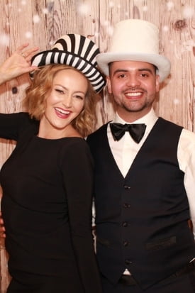 Couple wearing a striped hat and top hat at a rustic wood backdrop with a snow effect