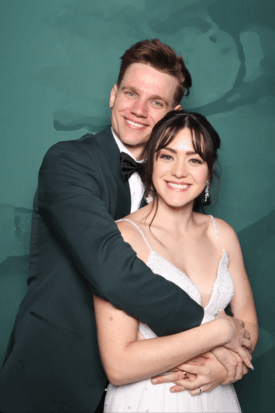 Couple embracing in front of a teal photo booth backdrop