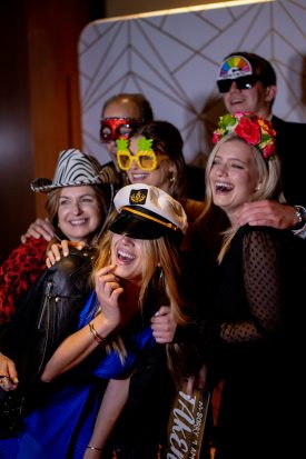 Group of guests laughing together with a captain hat, masks, and a flower crown
