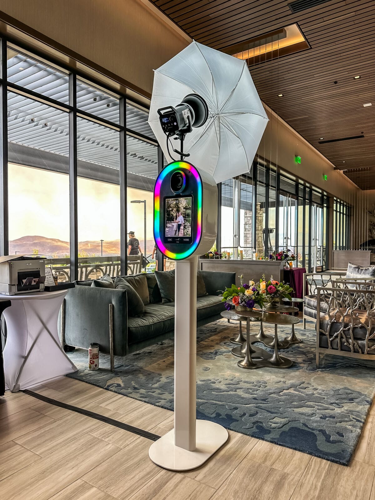 Photo booth with an umbrella light in an upscale indoor lounge with mountain-sunset windows