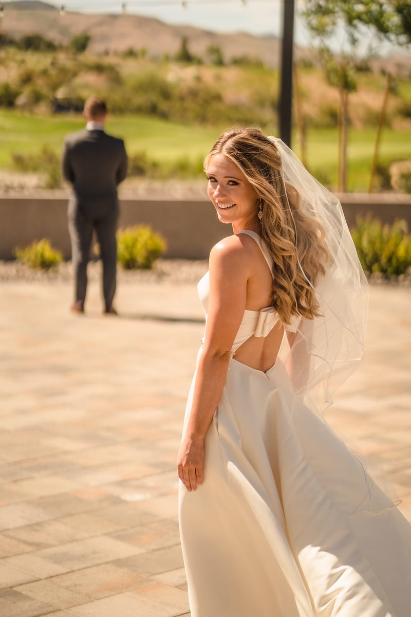 Bride glancing back over her shoulder during a first look while the groom faces away