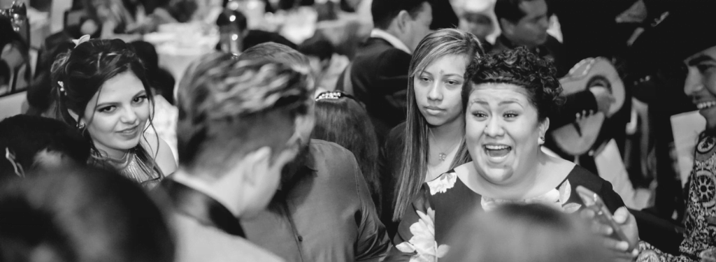 Candid black-and-white moment of guests laughing and mingling at a reception
