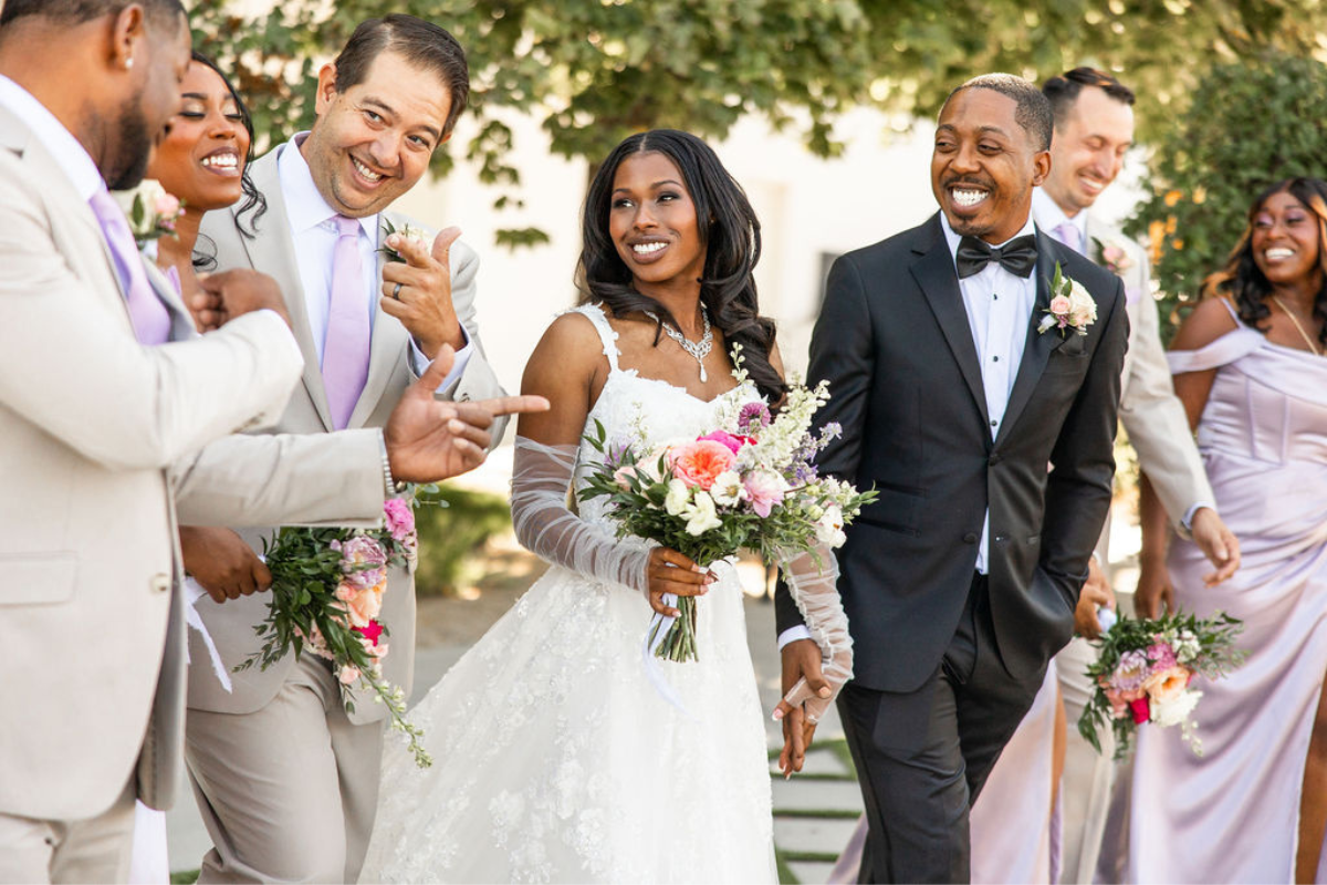 Wedding party walking together and laughing with the bride and groom in the center